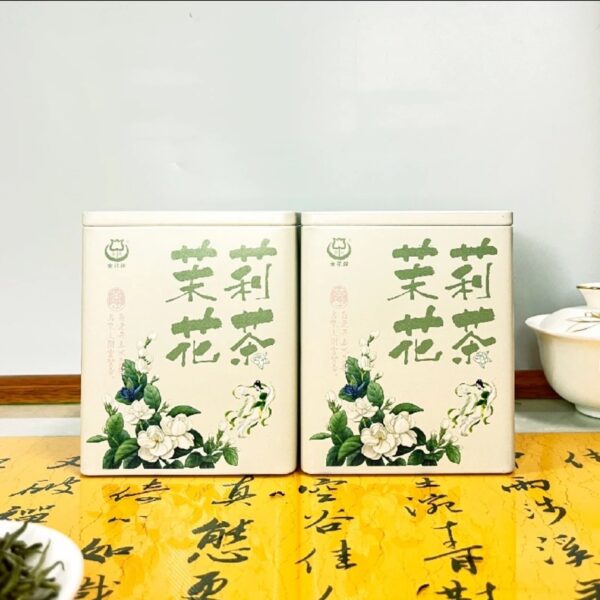 Two jasmine tea gift boxes with floral design on yellow Chinese calligraphy background