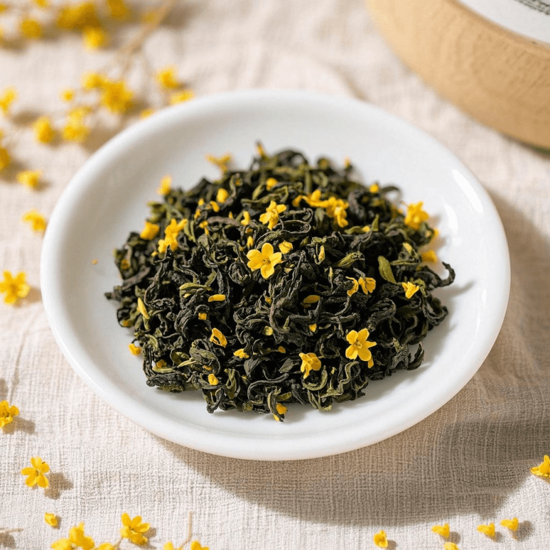 Close-up of osmanthus milk oolong tea leaves blended with dried golden osmanthus flowers on a white ceramic plate, highlighting texture and floral richness.